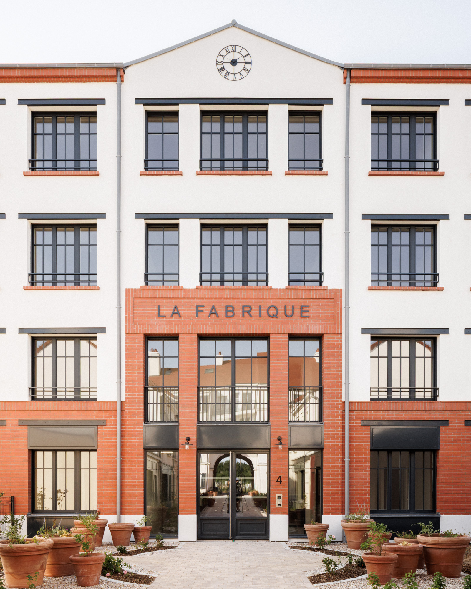 En fond de perspective du projet de logement collectif "la cour des artisans" par Cussac Architectes et Associés (CA+A) à Serris, un bâtiment - «La Fabrique» - affirme une écriture inspirée de l’architecture industrielle en R+3